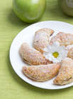 Snack recipes with apple turnovers on a white plate and green apple on a green tablecloth
