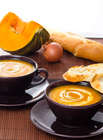 Easy Dinner Recipe with two cups of pumpkin soup, bread, onion and slice of pumpkin on a broun tablecloth