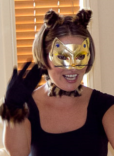 Halloween Costume of a woman dressed up as a cat in a black top black gloves golden cat mask and cat fur earband