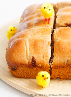 Hot Cross Buns on a wooden board with yellow toy chickens