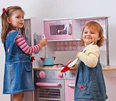 Two girls playing in a toy kitchen pretending cooking
