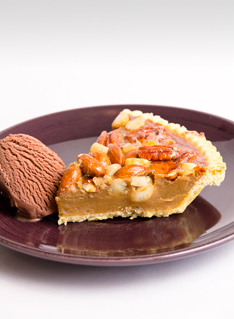 Slice of Butterscotch and Nut Tart on a burgundy plate with a scoop of chocolate icecream